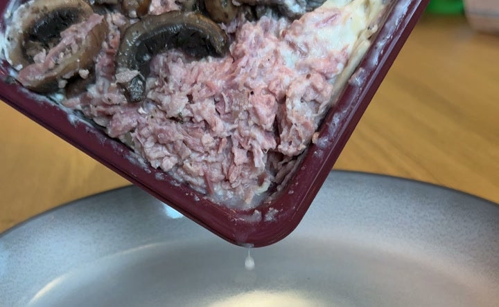 A supermarket ready meal being scraped out of its plastic tray onto a plate